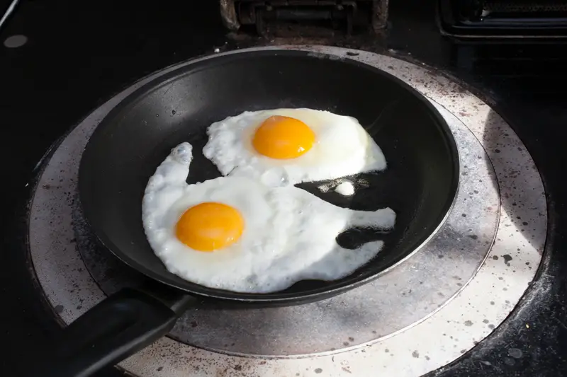 Two eggs frying in a pan on an aga top